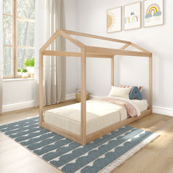 Children's wooden house bed with minimalist bedding in a bright, modern room featuring natural light and playful wall art.