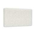 Close-up of white bouclé upholstered headboard showing textured fabric and rounded corner, modern minimalist bedroom furniture