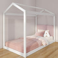 White wooden house-frame children's bed with pink bedding, upholstered headboard and letter "A" pillow in a modern kids' bedroom