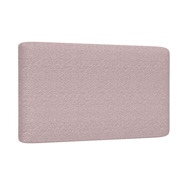 Close-up of blush pink upholstered headboard with textured fabric and rounded corners