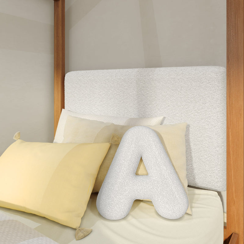 Neutral modern bedroom with textured linen headboard, pale yellow throw pillows, plush letter "A" cushion and wooden canopy bed frame