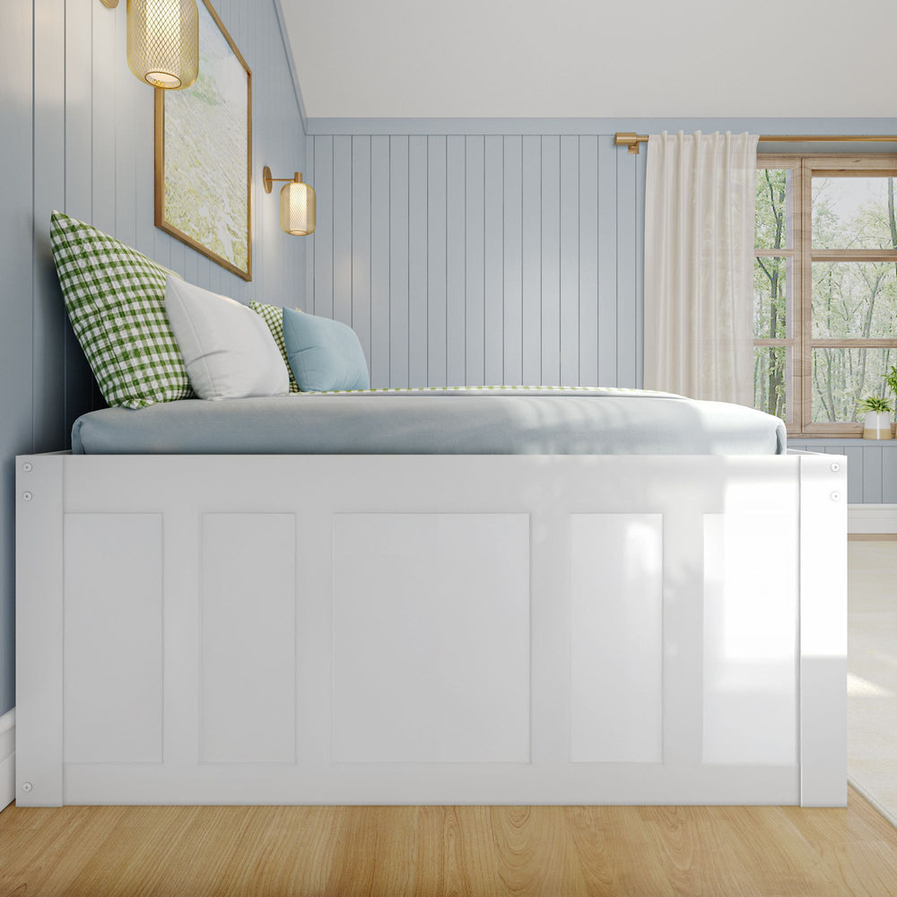 Cozy blue bedroom with panelled walls, white bedframe, and natural light from a large window.