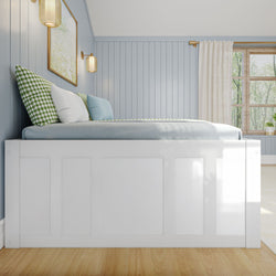 Cozy blue bedroom with panelled walls, white bedframe, and natural light from a large window.