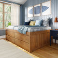 Cozy bedroom interior with natural wood storage bed, plaid bedding, layered throws and decorative pillows against a blue paneled accent wall