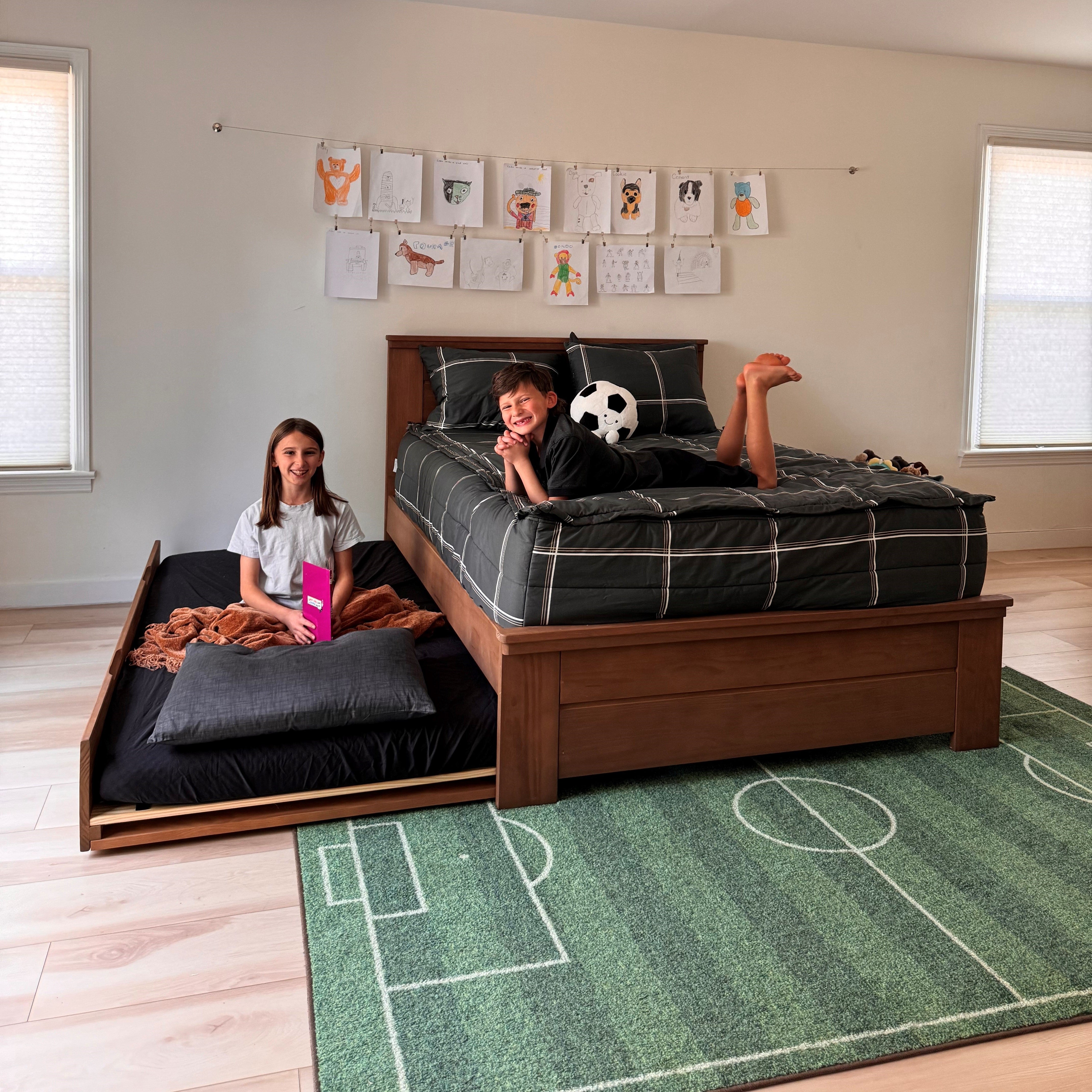 A bed with green bedding and two open storage drawers underneath.