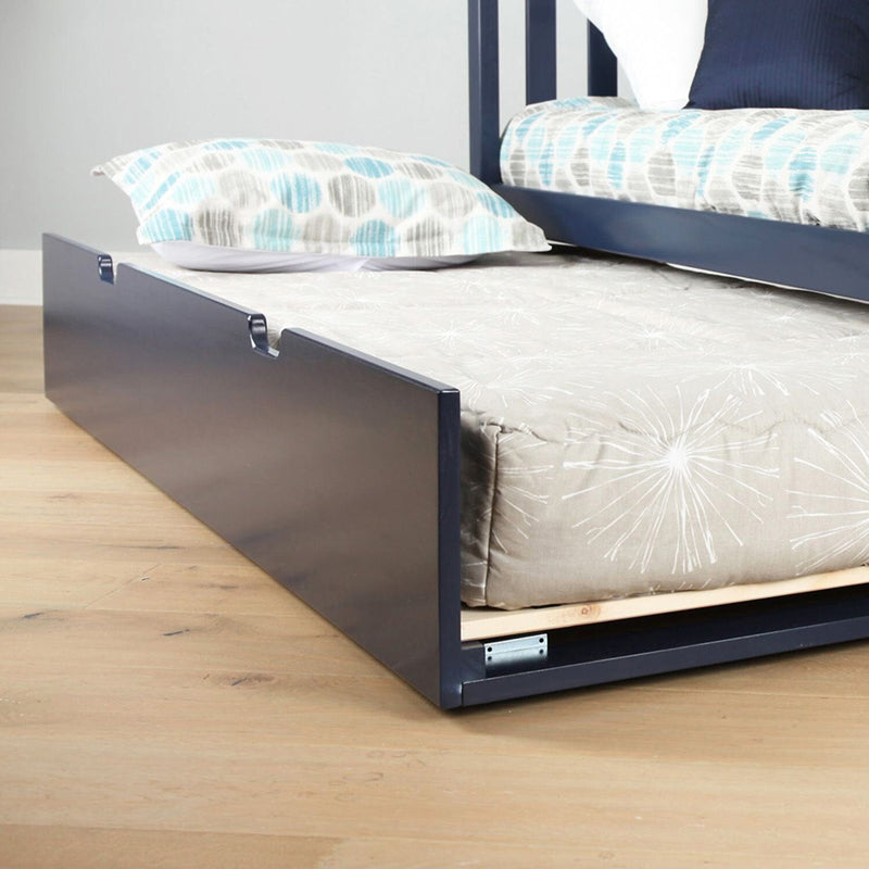 Navy blue wooden pull-out trundle bed drawer with mattress and gray patterned bedding under a twin bed — space-saving under-bed storage and extra sleeping solution for kids' bedroom
