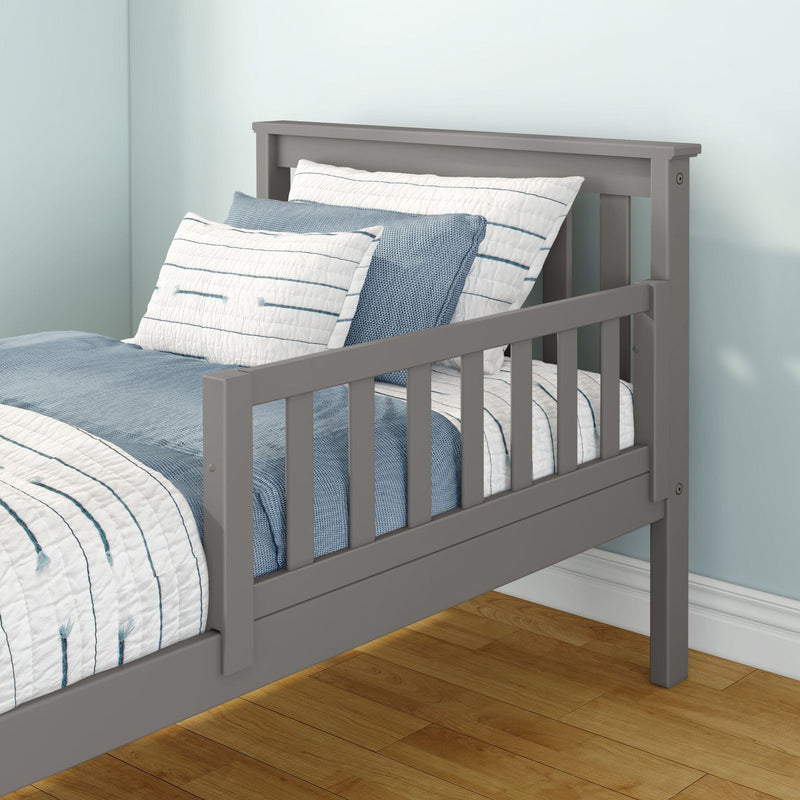 Gray wooden toddler bed with side safety rail and slatted headboard, dressed in blue-and-white striped bedding in a light-blue kids' bedroom with hardwood floor