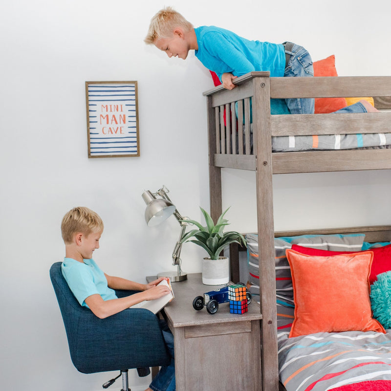 Boys loft bunk bed with built-in desk and study nook — child reading at desk, sibling on top bunk, toy car, Rubik's Cube and orange pillows in modern kids room decor