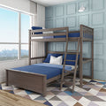 Modern gray wood twin-over-full bunk bed with ladder, blue bedding and white accent pillows in a light-blue paneled kids' bedroom with geometric rug and city-view window