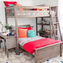 Gray wood bunk bed in kids' bedroom with colorful striped bedding and red quilt, accent pillows, ladder, toy display shelves, and small study desk