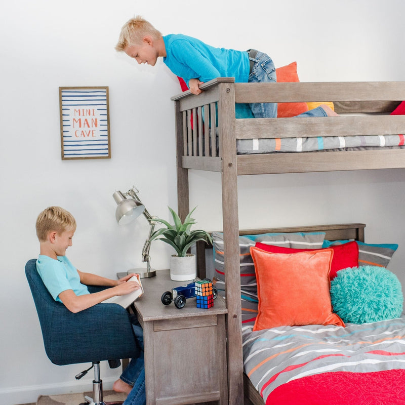 Kids bunk bed with built-in desk and study area — two boys reading and playing in a bright bedroom with colorful striped bedding, orange and teal pillows, toys and "Mini Man Cave" wall art