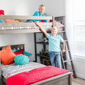 Kids bunk bed with two smiling boys on a wooden loft bed, colorful pillows and bedding, ladder and bright modern boys' bedroom decor