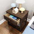 Dark wood nightstand with open drawer holding books, wooden birdhouse and mushroom-shaped lamps on hardwood bedroom floor beside bed