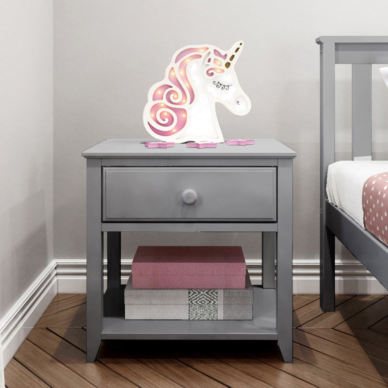 Gray bedside table with unicorn night light and books in a child's bedroom.
