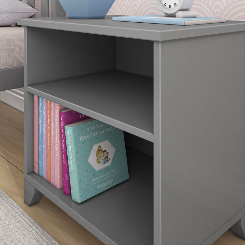 Grey wooden nightstand with shelves, holding children's books including "The Tale of Mrs. Tittlemouse" by Beatrix Potter, in a cozy bedroom setting.