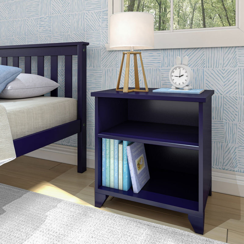 Blue wooden nightstand with books, lamp, and clock next to a bed in a modern bedroom with patterned wallpaper.