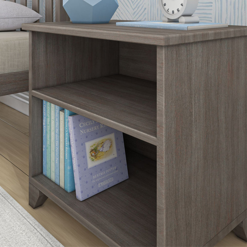 Dark wood bedside table with children's books and a modern clock on top.