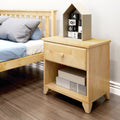 Wooden bedside table with drawer and open shelf next to a bed in a modern bedroom setting.
