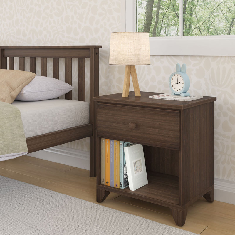 Wooden bedside table with books, lamp, and clock next to a bed in a cozy bedroom setting.