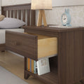 Wooden bedside table with drawer open, displaying books, lamp, and alarm clock for bedroom decor.