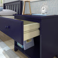 Navy blue wooden nightstand with open drawer and shelf featuring books and an alarm clock in a modern bedroom.