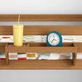 Wooden headboard shelf organizer with teal alarm clock and yellow tumbler cup on colorful geometric bedding