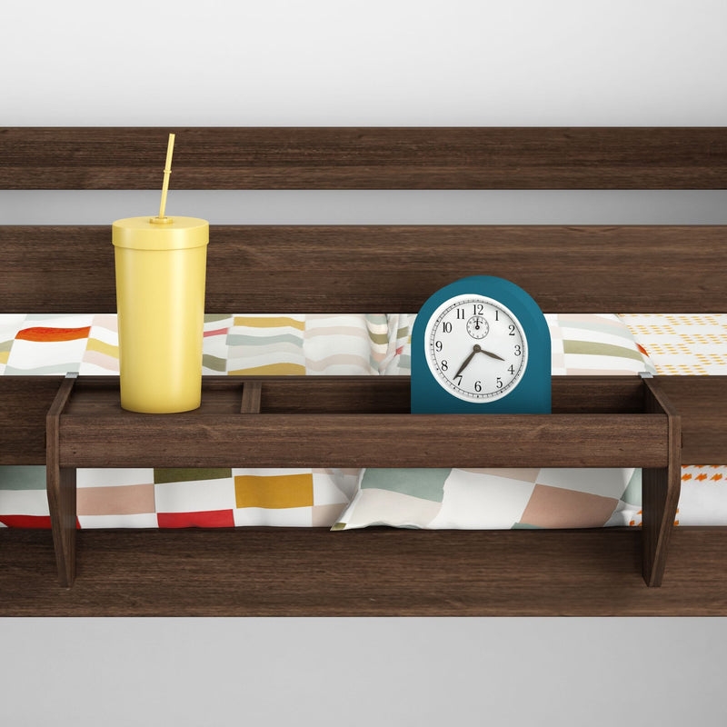 Wooden headboard shelf holding a yellow straw tumbler and blue alarm clock over colorful geometric-patterned bedding in a modern bedroom