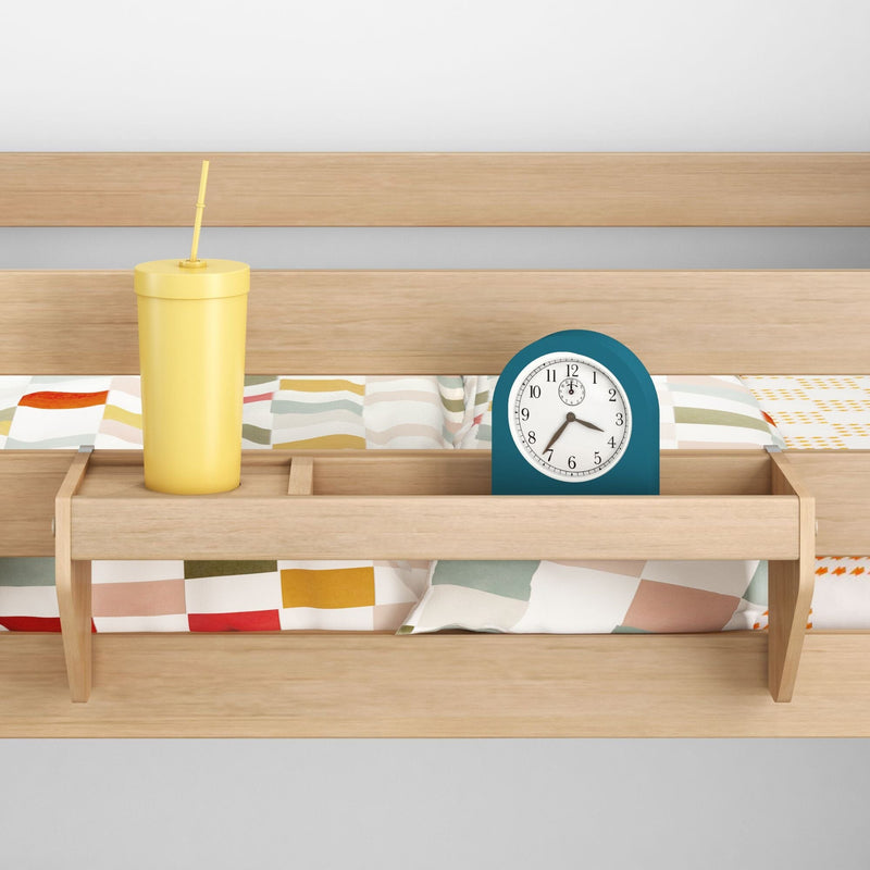 Wooden bunk bed bedside shelf organizer with blue alarm clock and yellow drinking tumbler on colorful patterned duvet
