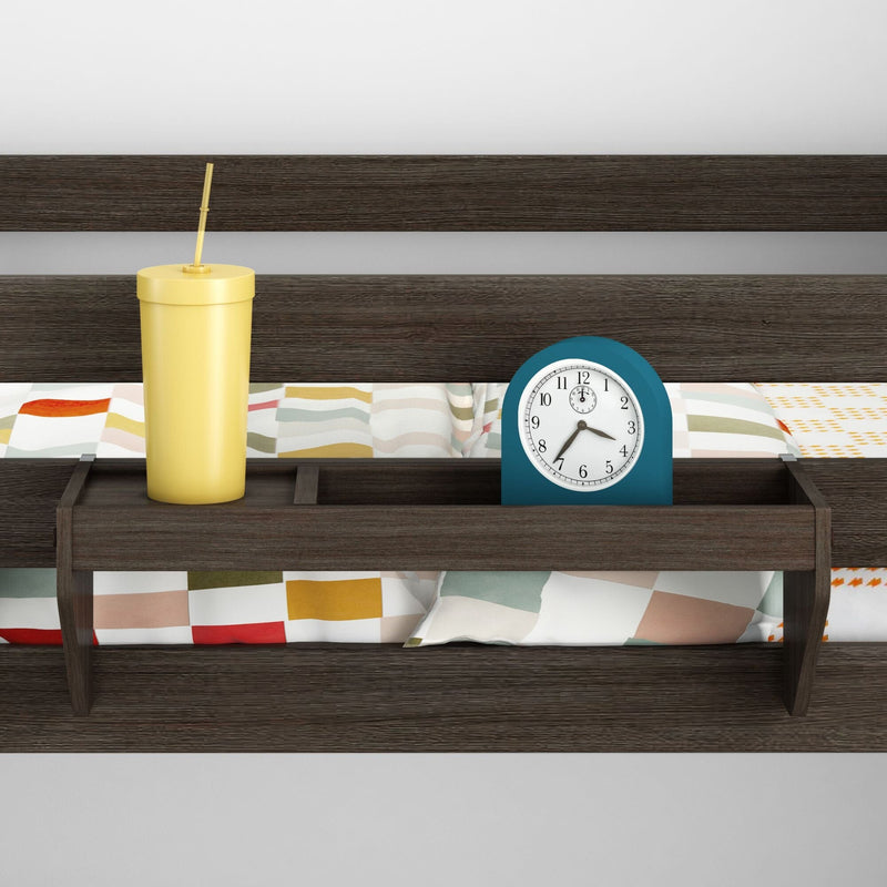 Wooden bedside shelf attached to headboard holding a blue analog alarm clock and yellow tumbler with straw on a modern bed with colorful geometric bedding