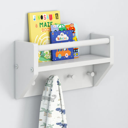 White wooden wall-mounted shelf with children's books and a hanging towel featuring dinosaur prints.
