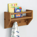 Wooden wall shelf with children's books and a dinosaur-patterned towel hanging.