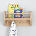 Wooden wall shelf with children's books and dinosaur-themed towel hanging.