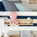 Stuffed pink octopus toy on a child's bed with striped and solid blue pillows.