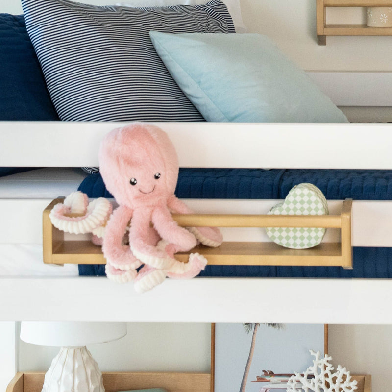 Stuffed pink octopus toy on a child's bed with striped and solid blue pillows.