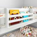 White children's bunk bed with built-in bookshelf holding colorful picture books, checkered pillows and patterned kids bedding