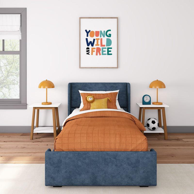 Kids bedroom with blue upholstered bed, orange quilted bedding, framed "Young Wild and Free" wall art, matching orange table lamps and nightstands