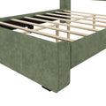 Green fabric-upholstered platform bed frame with exposed wooden slats and central support legs, modern low-profile design