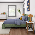 Children's bedroom with green upholstered bed, blue gingham bedding, orange bedside lamp, wall pennant, solar system poster, soccer ball and white dresser with books
