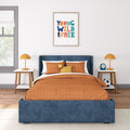 Kids bedroom decor: blue upholstered headboard, orange quilted bedding, plush lion toy, bedside lamps and "Young Wild and Free" framed wall art