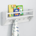 White wall-mounted shelf with children's books and a hanging towel featuring dinosaur designs.