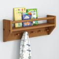 Wall-mounted wooden kids shelf holding colorful children's board books (dinosaur maze, dinosaur book, vehicles) with four coat pegs below and a dinosaur-print blanket — nursery storage and wall organizer