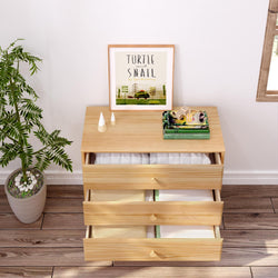 Wooden dresser with open drawers displaying linens, decorated with a plant and framed artwork titled "Turtle and Snail.