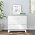 White three-drawer nursery dresser with pastel alphabet wall art, wooden pull toy horse, stacked children's books and alphabet blocks on top in a bright modern kids' room with potted plant and window
