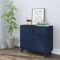 Navy blue three-drawer dresser in a modern nursery with wooden toy horse, framed colorful alphabet print, children's books and a potted plant on hardwood floor