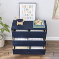 Navy blue three-drawer nursery dresser with folded baby clothes inside, wooden toy horse and stacked children's books on top, pastel framed alphabet poster, potted plant and hardwood floor — kids room storage and nursery decor