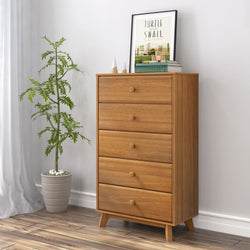 Mid-century modern five-drawer natural oak dresser (tall chest) in minimalist bedroom with potted plant and framed art