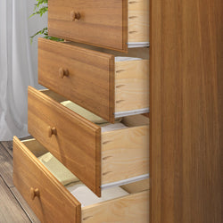 Solid natural wood dresser with several open drawers revealing neatly folded towels and linens, bedroom chest of drawers on hardwood floor