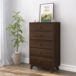 Mid-century modern wooden dresser with potted plant, books, and framed art decor in a stylish bedroom interior.