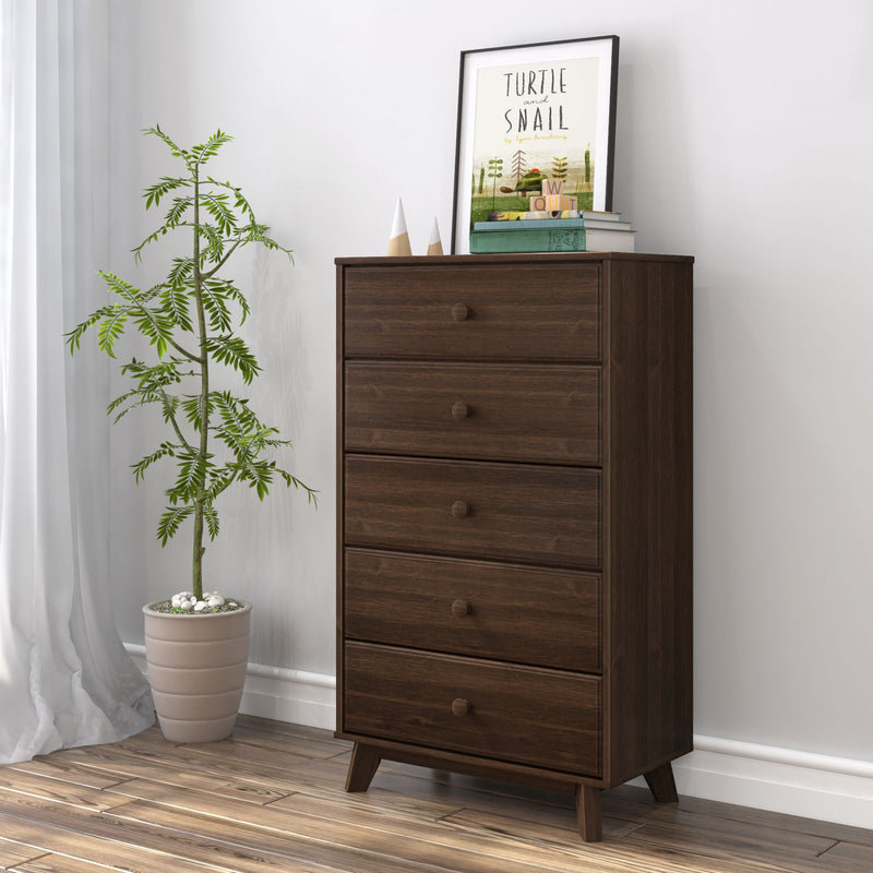 Mid-century modern wooden dresser with potted plant, books, and framed art decor in a stylish bedroom interior.