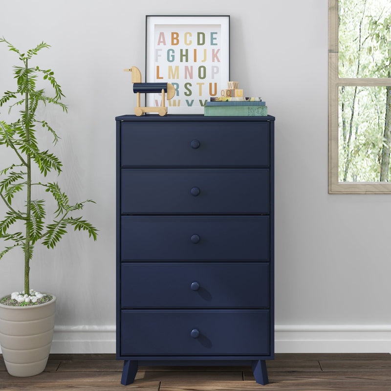 Navy blue five-drawer tall dresser in a modern nursery with framed colorful ABC print, wooden toy horse, stacked books, potted plant and window